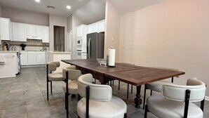 Una cocina moderna con armarios blancos, una mesa de madera y seis sillas.