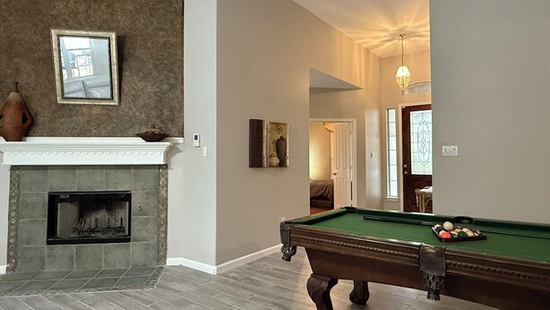 Una habitación con chimenea, mesa de billar y un pasillo que conduce a otra estancia.