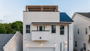 A modern two-story house with a white exterior, a garage, and a small balcony with string lights.
