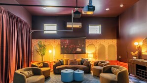 A modern living room with a sofa set, ottomans, and a flat-screen TV.