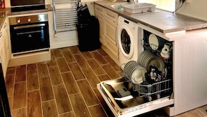 A compact kitchen with a built-in oven, a washing machine, and a sink.