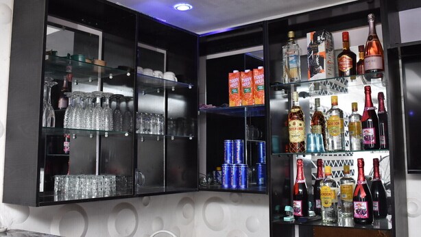 A bar area with shelves of liquor bottles, glasses, and canned beverages. - MC RICA HOTEL (Ikorodu)