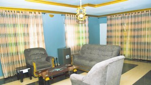 A living room with a sofa, armchairs, a coffee table, and curtains. - MC RICA HOTEL (Ikorodu)