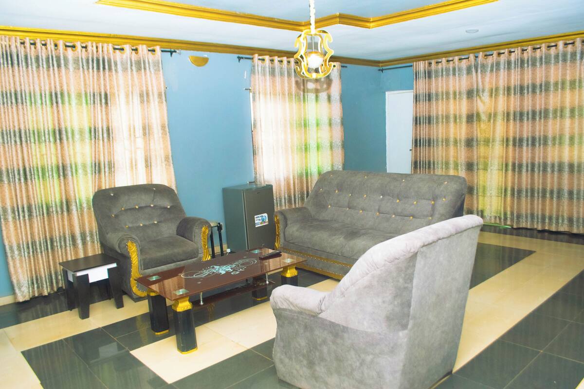 A living room with a sofa, armchairs, a coffee table, and curtains.