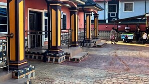 A building with a tiled roof and a red and yellow facade. - MC RICA HOTEL (Ikorodu)