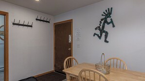 A dining area with a wooden table and chairs, a decorative metal sculpture, and a coat rack with hooks. - Budget-Friendly Purgatory Condo, Steps to Lift, Hot Tub, w/ Pool & Gym Access (Durango)