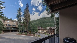 A view from a balcony overlooking a parking area with buildings, trees, and a mountain in the background. - Budget-Friendly Purgatory Condo, Steps to Lift, Hot Tub, w/ Pool & Gym Access (Durango)