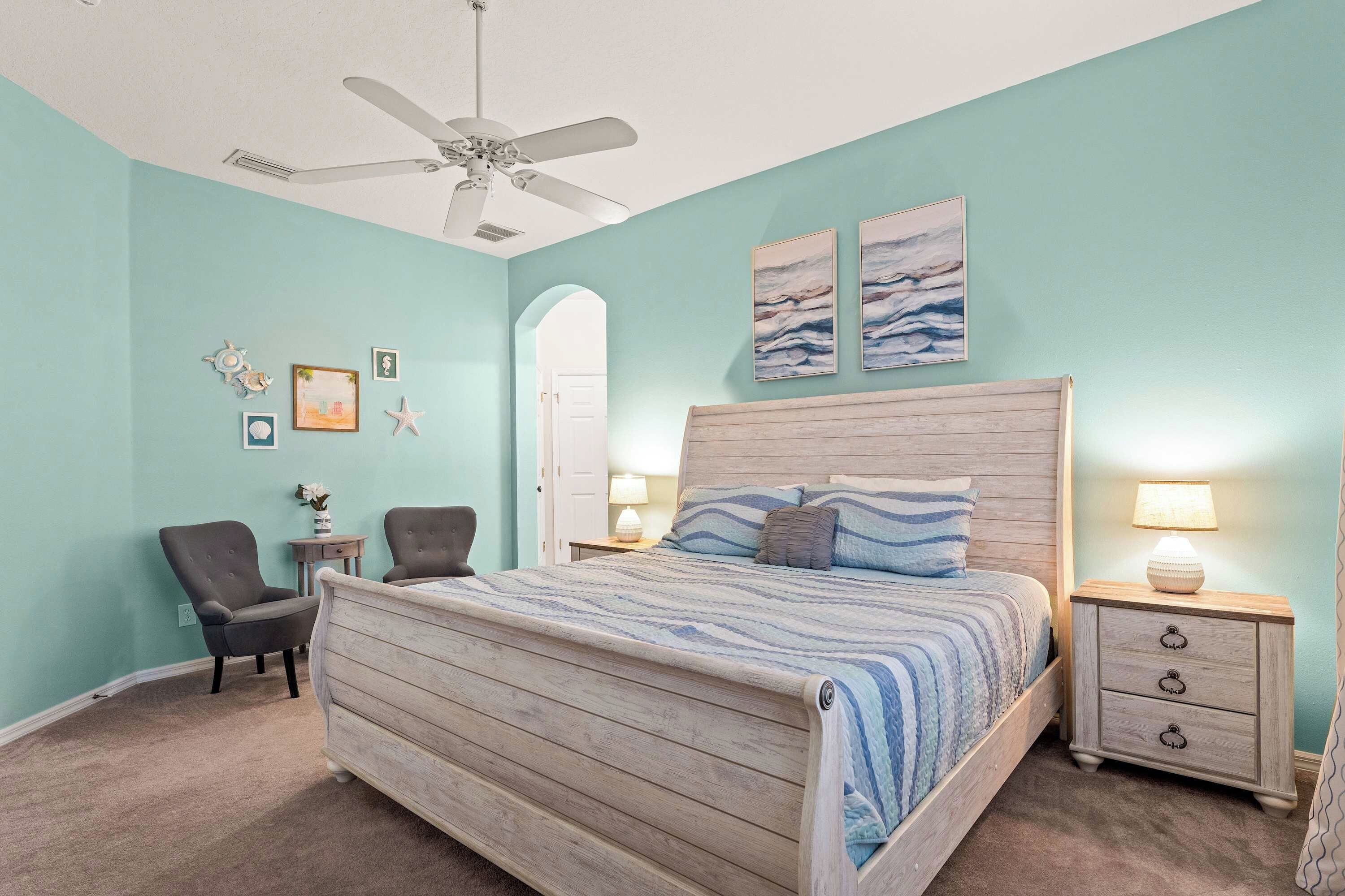 A bedroom with a wooden bed, two bedside tables, a ceiling fan, and artwork on the wall.