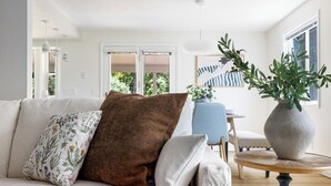 A living room with a sofa, a blue chair, a round wooden table, and a large vase with green plants. - Perfect for Families & Pets, Garage Parking, Stylish Renovation, Sleeps 10 (Boise)