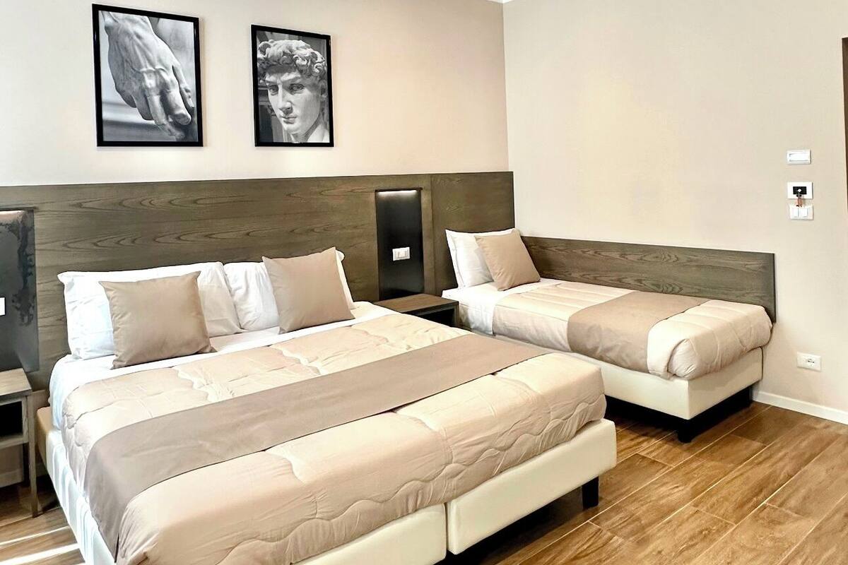Una habitación de hotel con dos camas, suelo de madera y dos cuadros en la pared.