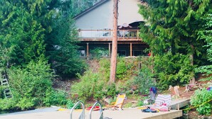 En brygga som sträcker sig ut i vattnet, med ett hus i bakgrunden omgivet av täta träd.