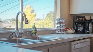 Una cocina moderna con un lavamanos de acero inoxidable, una cafetera y un dispensador de jabón.