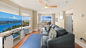 Een moderne woonkamer met een groot raam dat een prachtig uitzicht biedt op een berg en een meer.