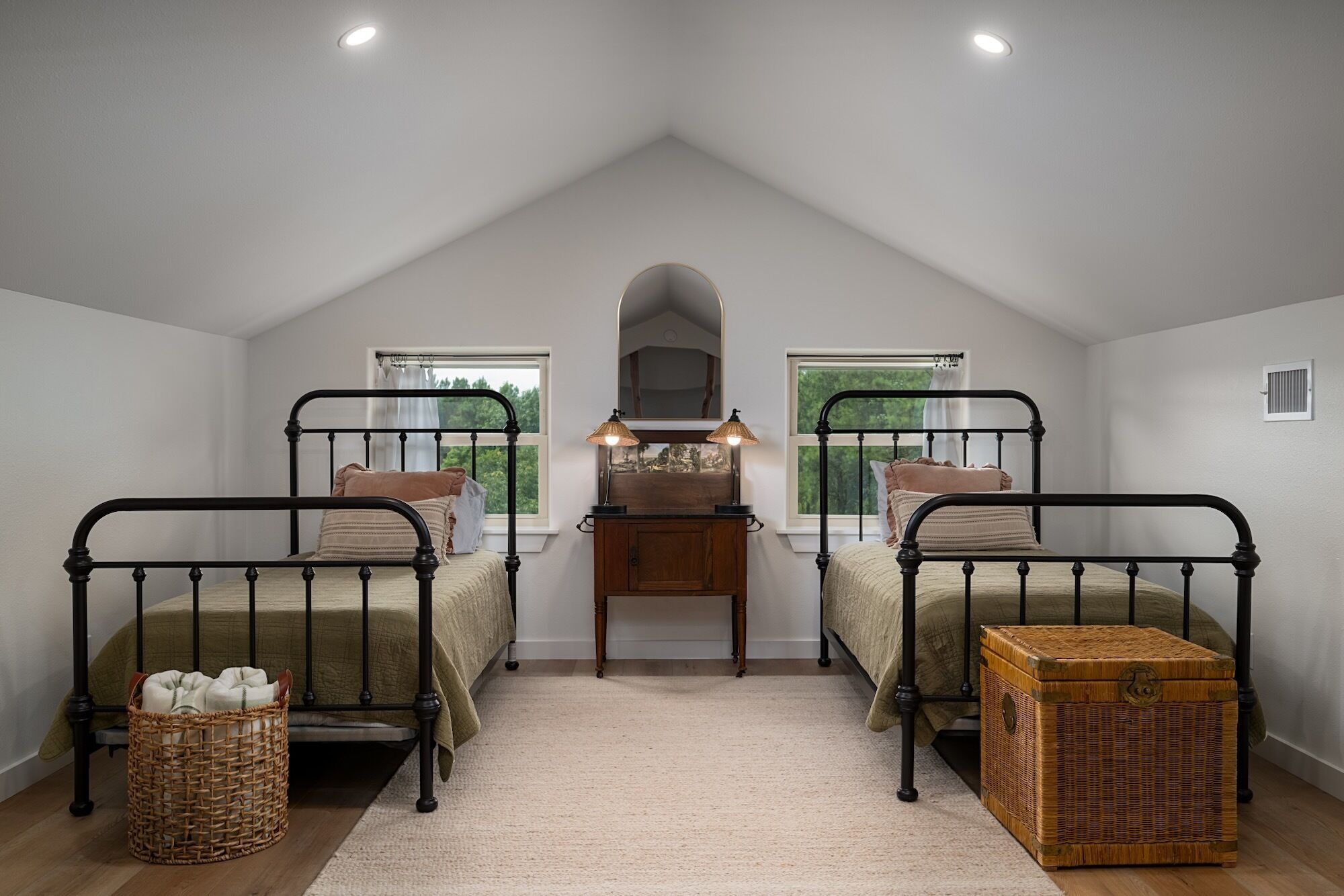 Une chambre avec deux lits, une commode, un miroir et une fenêtre.