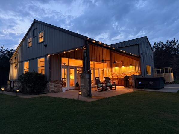 A two-story building with a covered patio area, stone pillars, and a grill station.