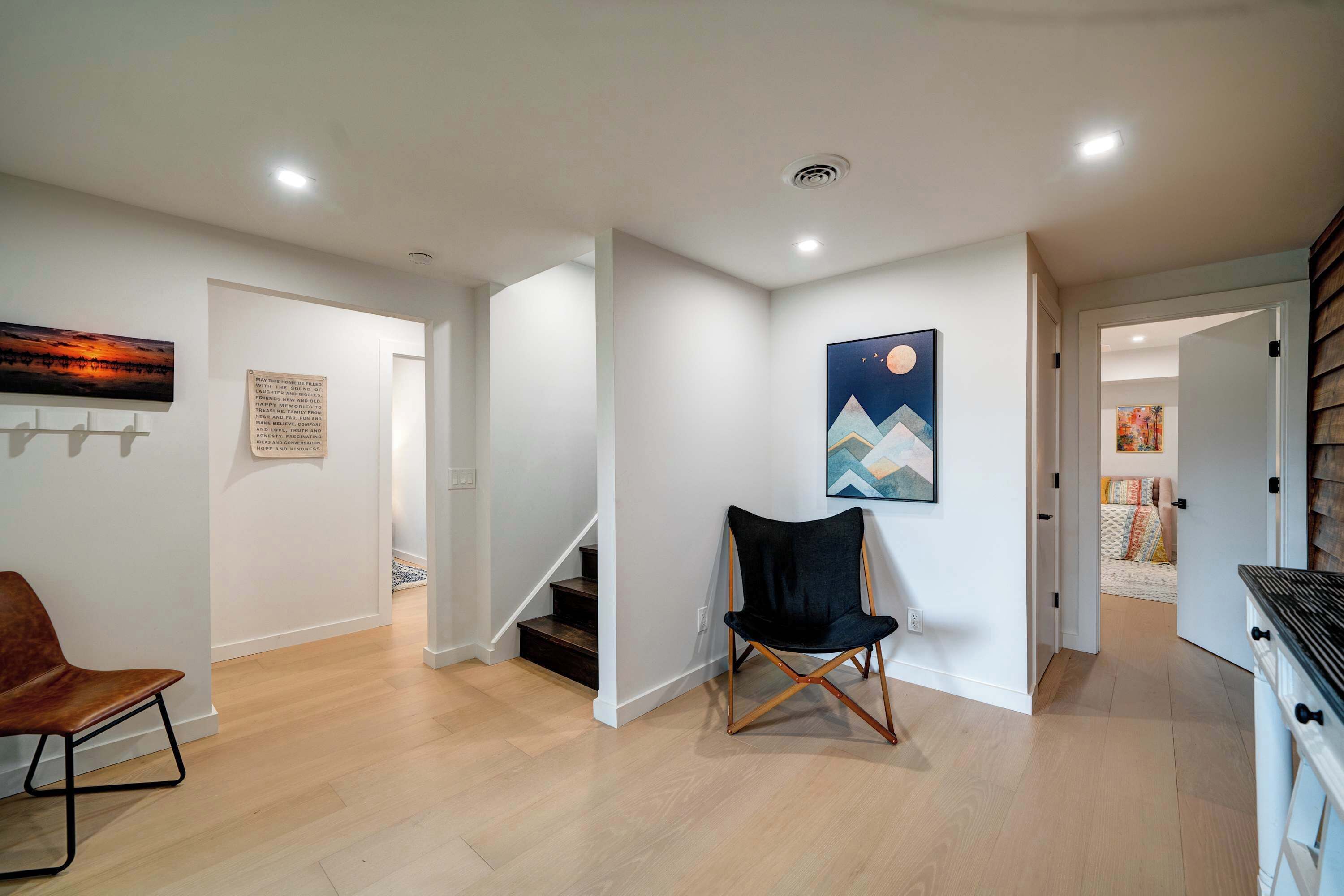 Ein modernes Interieur mit Treppe, einem schwarzen Klappstuhl und Kunstwerken an den Wänden.