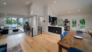 Un amplio salón con suelo de madera, una mesa de comedor y una zona de cocina con barra.