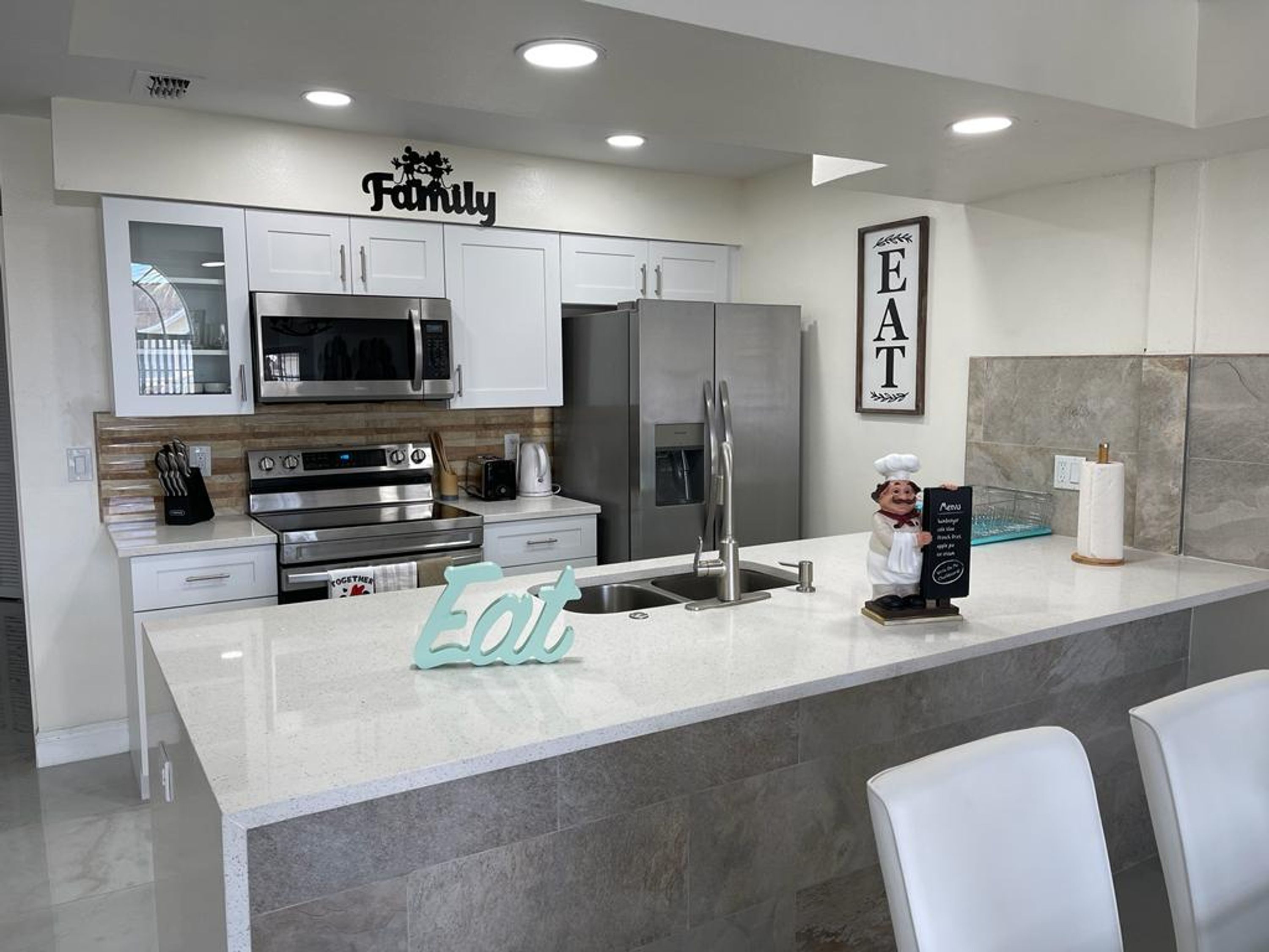 Una cocina moderna con armarios blancos, electrodomésticos de acero inoxidable y una isla central.