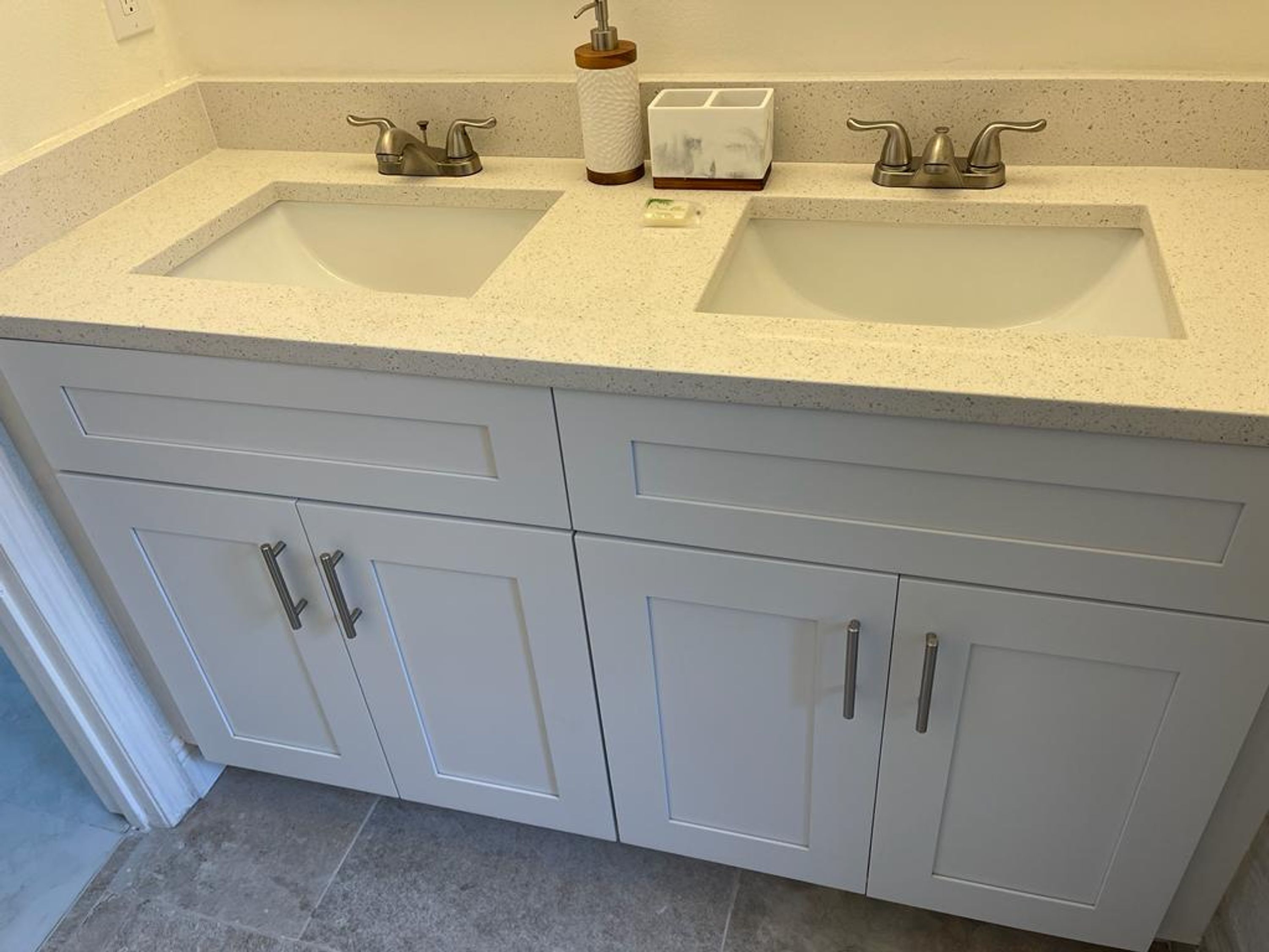 Une salle de bain avec deux lavabos, un distributeur de savon et un porte-brosse à dents.