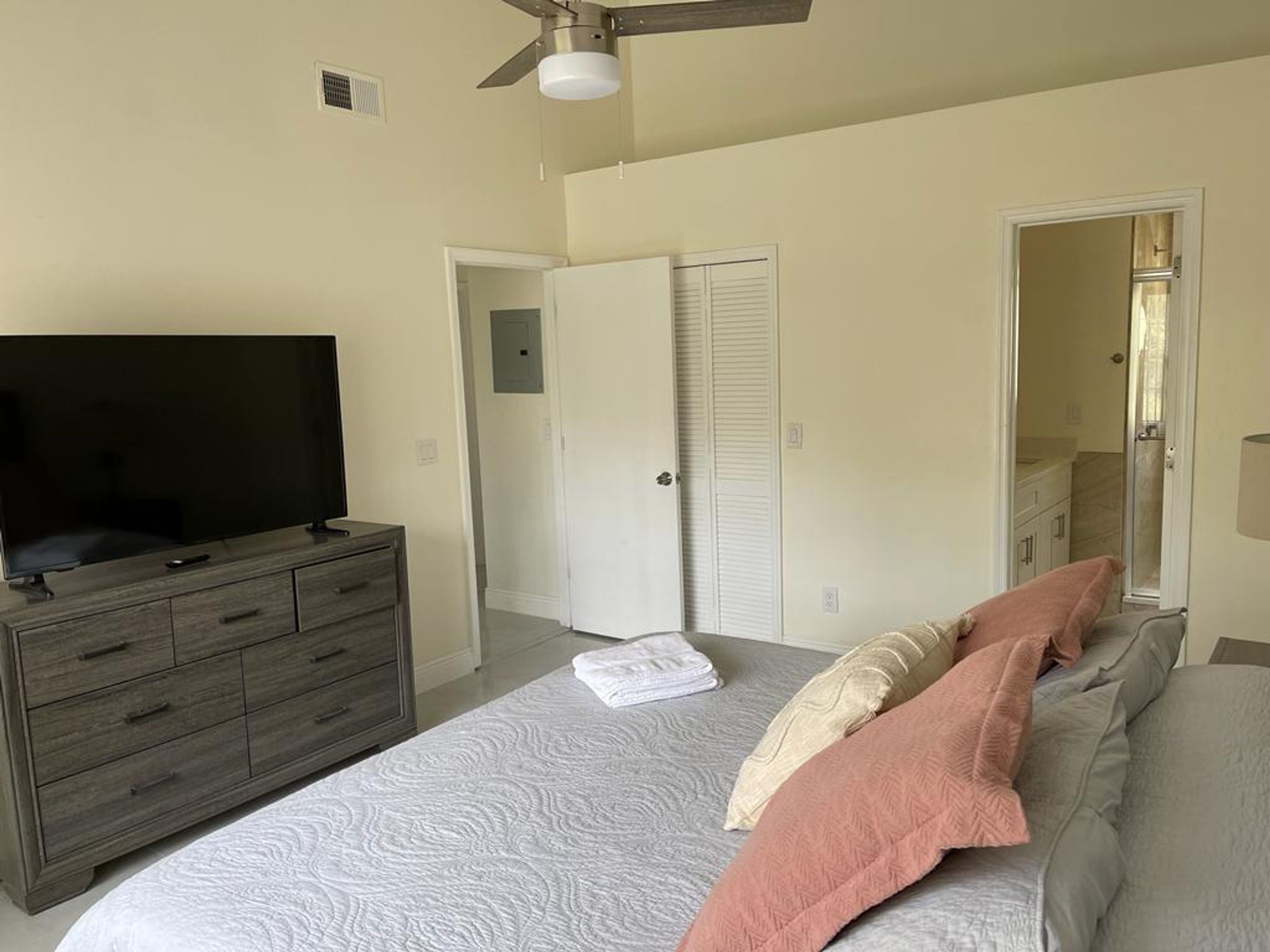 Une chambre à coucher avec un lit, un téléviseur posé sur une commode et un placard.