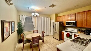 A compact kitchen with a dining area, featuring a refrigerator, microwave, stove, and a small sink. - Luxury Compass 3BR Townhouse Near Disney Parks 2 (Kissimmee)