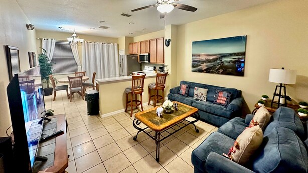 A living room with a sofa, coffee table, TV, and a ceiling fan. - Luxury Compass 3BR Townhouse Near Disney Parks 2 (Kissimmee)