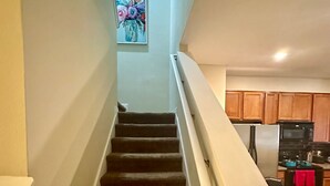 A staircase leading to a kitchen with wooden cabinets and a refrigerator. - Luxury Compass 3BR Townhouse Near Disney Parks 2 (Kissimmee)