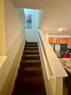 A staircase leading to a kitchen with wooden cabinets and a stainless steel refrigerator. - Luxury Compass 3BR Townhouse Near Disney Parks 2 (Kissimmee)