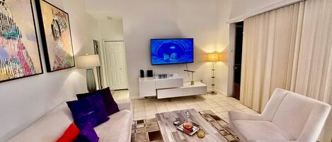 A modern living room with a flat-screen TV, white sofa, and a coffee table.