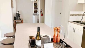Una cocina moderna con una isla central, una cafetera, una botella de vino y un salero y pimentero.