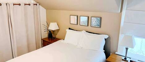 A hotel room with a bed, a nightstand, a lamp, a clock, and a ceiling fan.