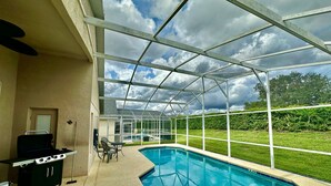 Un espace piscine extérieur abrité, équipé d’un barbecue et de sièges.