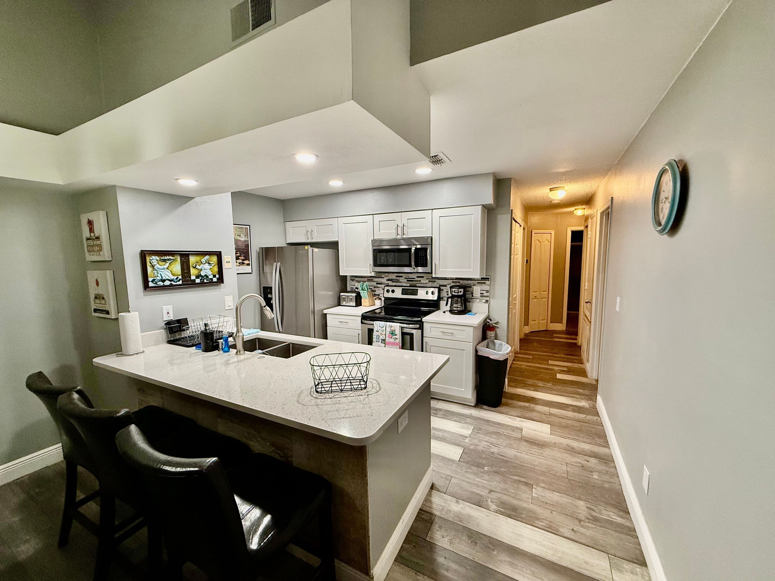 A modern kitchen with white cabinetry, stainless steel appliances, and a central island.