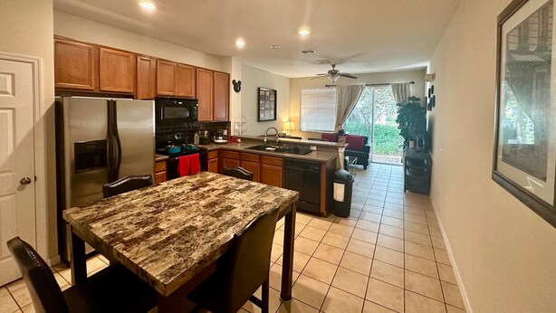 A modern kitchen with wooden cabinets, a stainless steel refrigerator, and a granite countertop. - Grand Resort 3BR Compass Townhouse Near Disney 1 (Kissimmee)