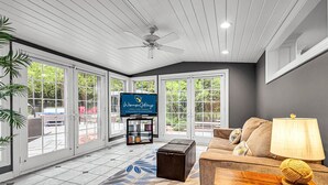 A spacious living room with a large TV, comfortable seating, and a view of the outdoors. - Lighthouse | 9BR Resort · Pool · Arcade · Hot Tub (Saukville)