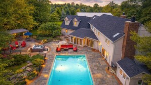 A residential property with a swimming pool, patio furniture, and a covered outdoor seating area. - Lighthouse | 9BR Resort · Pool · Arcade · Hot Tub (Saukville)