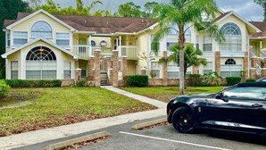 A two-story residential building with a symmetrical facade, large windows, and a central entrance with steps. - Disney Somerset 3BR Condo Near Theme Parks (Kissimmee)