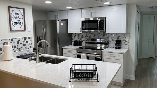 A modern kitchen with white cabinets, stainless steel appliances, and a coffee station. - Disney Somerset 3BR Condo Near Theme Parks (Kissimmee)