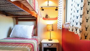 Une pièce confortable avec un lit, une table de chevet avec une lampe et une fenêtre avec des rideaux.