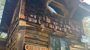 Una cabaña de troncos con un letrero que dice 'HEMINGWAY', revestimiento de madera y una ventana.