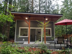 A modern cabin with a wooden deck, large windows, and a red umbrella. - Madrona Cabin 1-bedroom cabin in Sequim (Sequim)