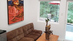 A modern living room with a brown sofa, a wooden coffee table, and a painting on the wall. - Madrona Cabin 1-bedroom cabin in Sequim (Sequim)
