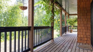 Une terrasse en bois avec un mur en briques, une jardinière suspendue et une plante en pot.