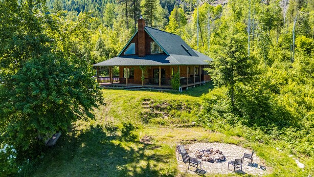 Une cabane dotée d’un porche, entourée d’une forêt dense.