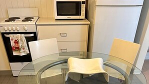 Eine Küche mit Glastisch, vier Stühlen, Herd und Mikrowelle.