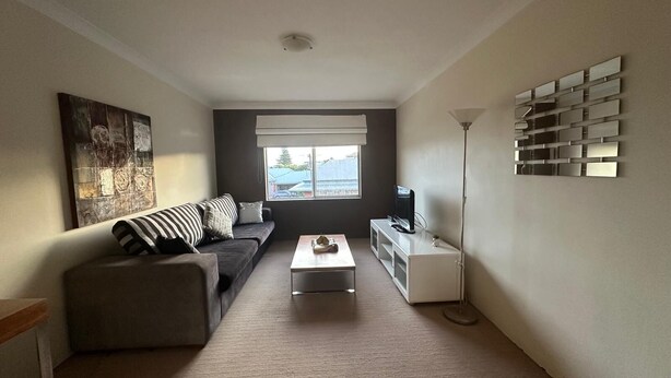 Ein modernes Wohnzimmer mit Sofa, Couchtisch, Fernseher und Kunstwerk an der Wand.
