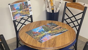 Een ronde houten tafel met een kleurrijk puzzelspel in het midden, omringd door blauwe fauteuils.