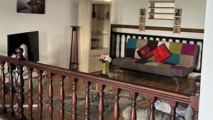 A living room with a wooden ceiling, a sofa with colorful cushions, a TV, and a painting on the wall. - T3 cosy villa top 2 bedrooms (Les Abymes)