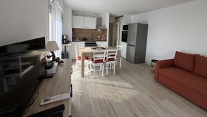 Un espacio habitable compacto con kitchenette, comedor y sofá.
