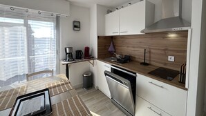 Una cocina moderna con armarios blancos, encimera de madera y horno empotrado.